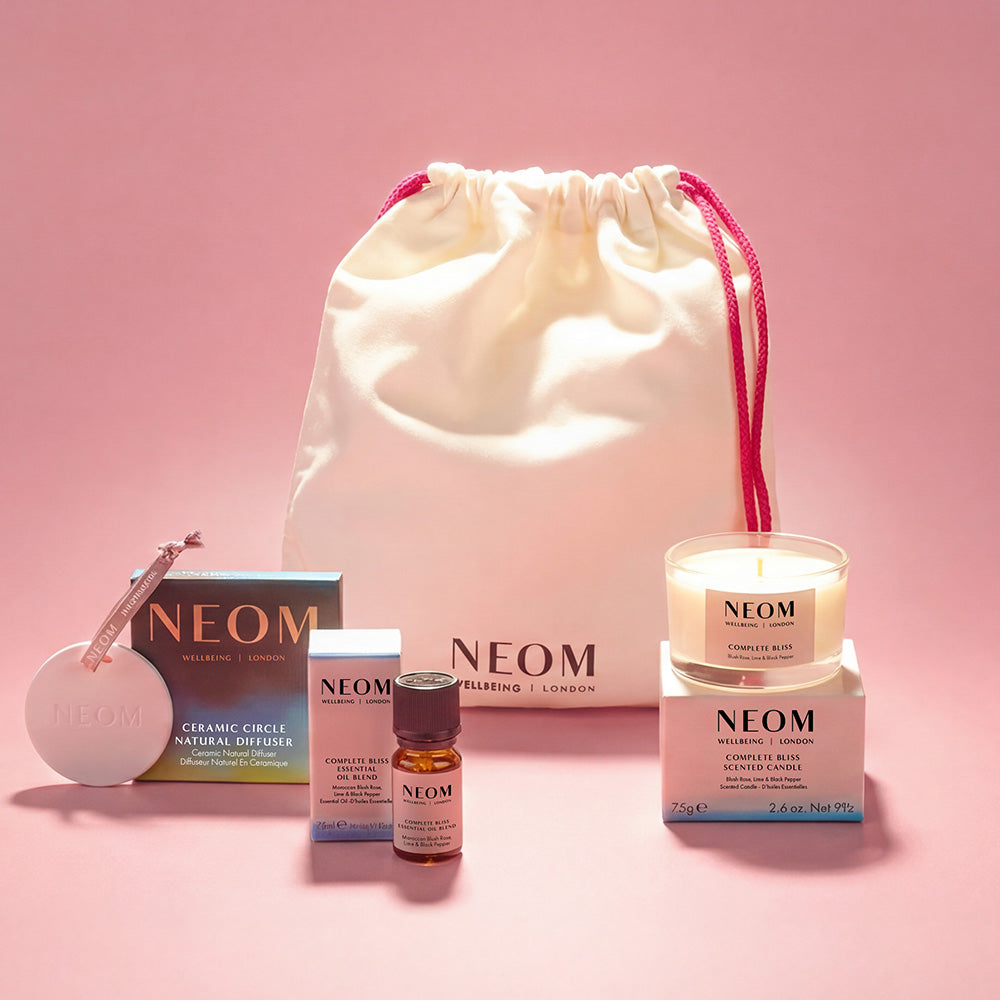 NEOM products and drawstring bag on a purple background