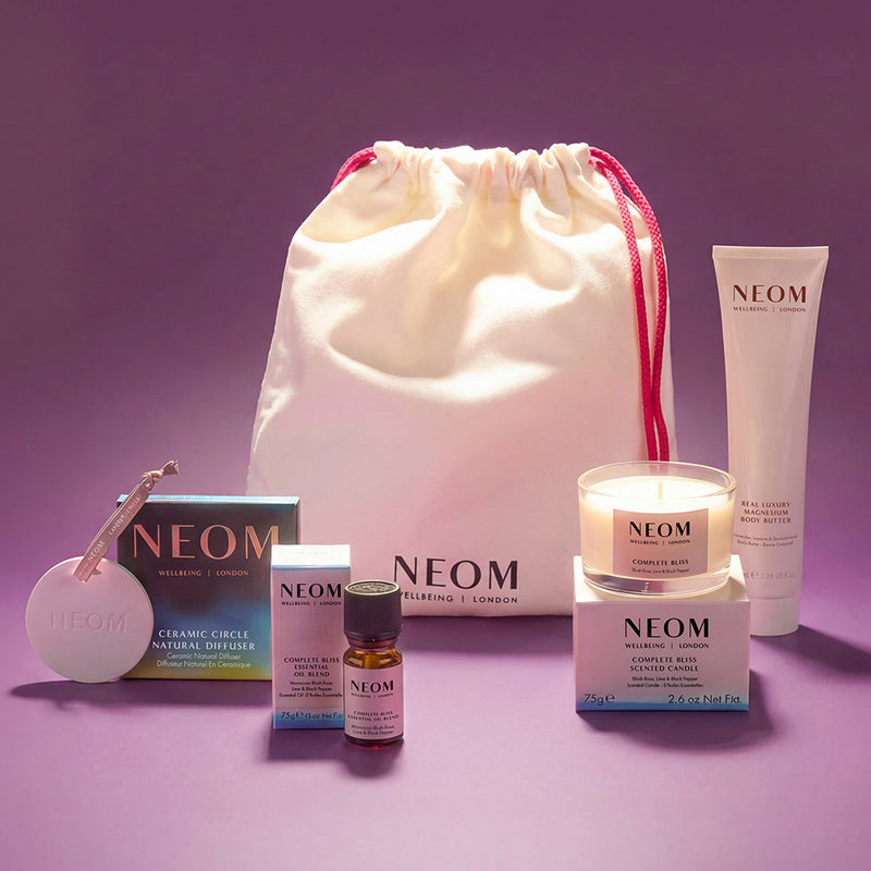 NEOM products and drawstring bag on a purple background