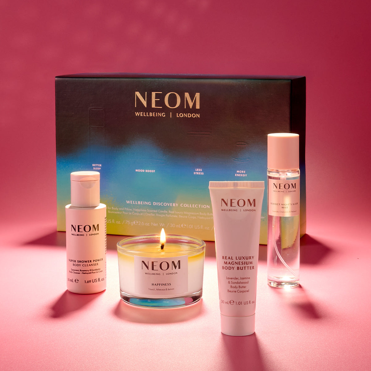 NEOM skincare products including a candle, skincare and a sleep mist on a pink background