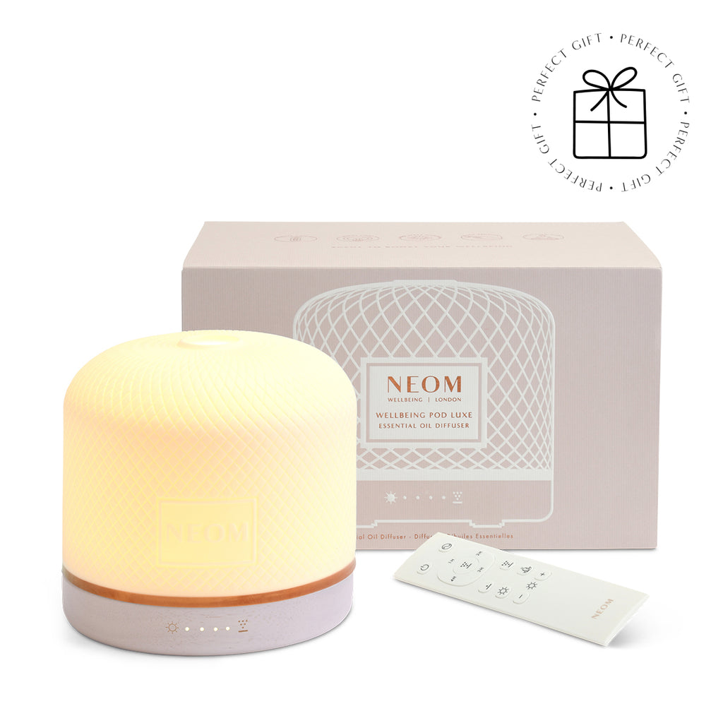 NEOM essential oil Pod Luxe diffuser with packaging on a white background with a Perfect Gift roundel with a present