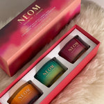 NEOM Winter Wellbeing Candle Trio gift set with three colourful candles in red box on soft fur surface