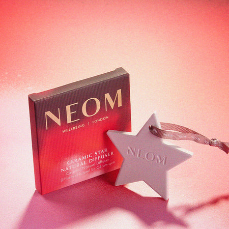 NEOM ceramic star diffuser with packaging on a pink background