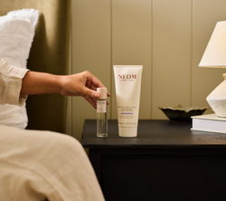 NEOM Sleep Mist and Body Butter placed on a bedside table