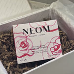 NEOM It’s All Rosy candle packaged in a gift box on decorative wrapping